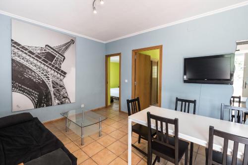 a living room with a table and a tv on the wall at Camping Los Llanos in Denia