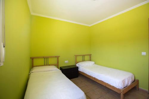 two beds in a room with green walls at Camping Los Llanos in Denia