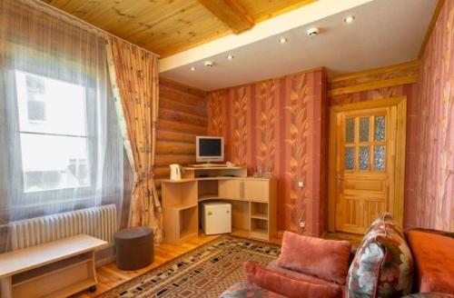 sala de estar con sofá, TV y ventana en BKC Country, en Sosnoviy Bor