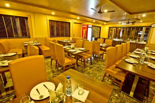 a restaurant with wooden tables and chairs in a room at Quartz Himalayan Brothers in Dharamshala