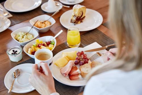 een vrouw die aan een tafel zit met een bord eten bij Berglodge Grossarl in Grossarl
