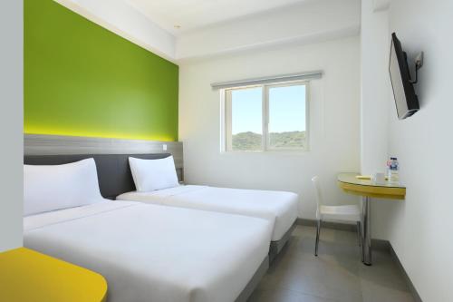 two beds in a room with a green wall at Amaris Hotel Padang in Padang