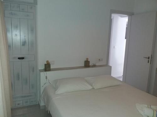 a white bedroom with a bed and a window at Studios Kontos in Mikri Vigla