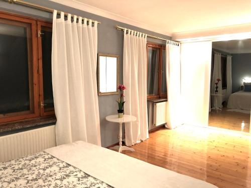 a bedroom with white curtains and a table and a bed at Sielanka w Brennej in Brenna