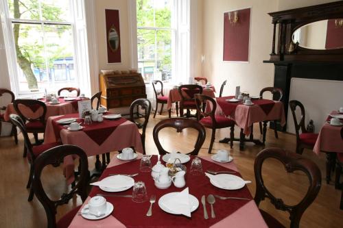 a dining room with tables and chairs with red tablecloths at Clifton Hotel in Glasgow