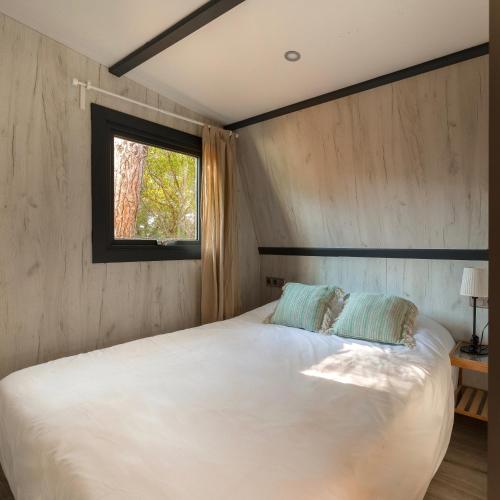 a bedroom with a large white bed with a window at HolaCamp Sitges Garrofer in Sitges