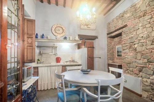 cocina con mesa, sillas y pared de piedra en Una Terrazza nel Centro Storico en Barga