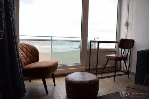 a living room with a chair and a window at Residentie Les Algues 8ste verdieping in Blankenberge