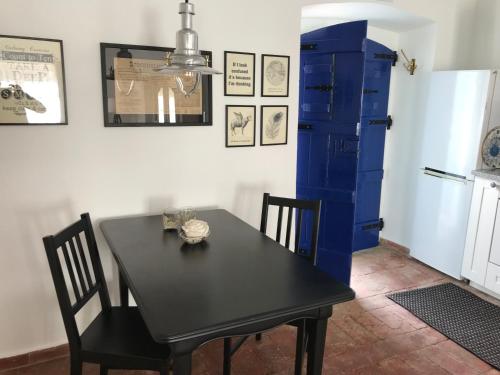 a dining room with a black table and a blue cabinet at Studio Colina in Tavira