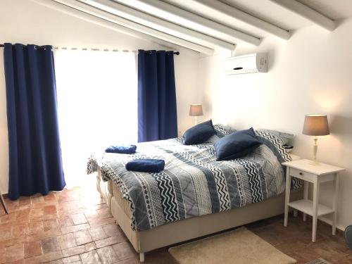 a bedroom with a bed and a window with blue curtains at Studio Colina in Tavira