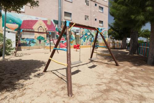 a swing set in a playground in front of a mural at Camping Los Llanos in Denia