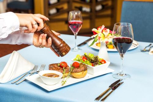 a table with a plate of food and glasses of wine at Landmark Creek Hotel Plovdiv in Plovdiv
