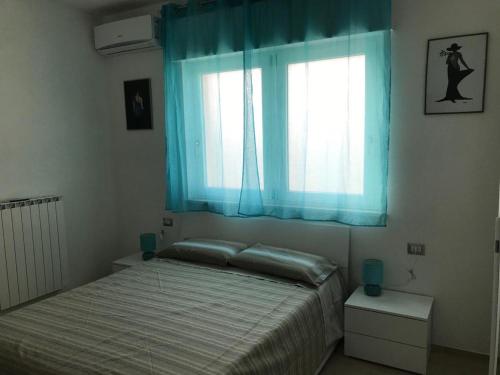 a bedroom with a bed and a window with blue curtains at B&B Oleum in Terlizzi