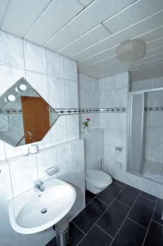 a white bathroom with a sink and a toilet at Hotel Altbacher Hof in Altbach