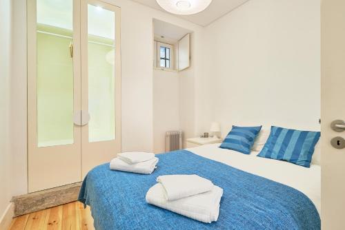 a bedroom with a blue and white bed with towels on it at Casa Eclea Lisbon Principe Real in Lisbon