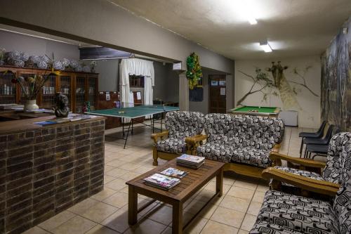 a living room with couches and a ping pong table at Khaya La Manzi Guest Lodge in Hibberdene