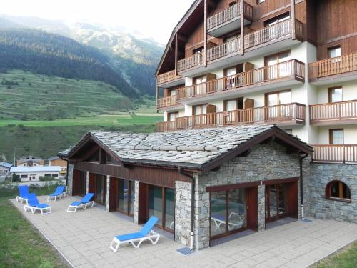 a hotel with chairs and a balcony and a building at Lagrange Vacances Les Valmonts de Val Cenis in Lanslebourg-Mont-Cenis