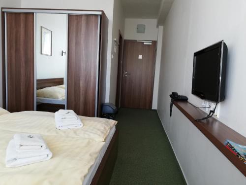 a hotel room with a bed and a flat screen tv at Hotel Klar in Liptovský Mikuláš