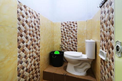 a bathroom with a toilet and a trash can at Ombey Guest House in Bogor