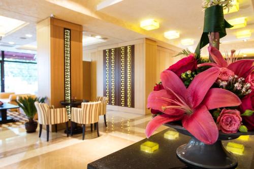 a vase of flowers on a table in a lobby at Landmark Creek Hotel Plovdiv in Plovdiv