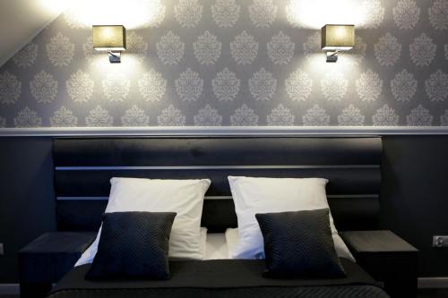 a bed with two pillows and two lights on a wall at Hotel Bellis in Lublin