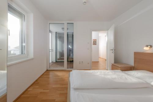 a white bedroom with a bed and a window at Appartements Ramsau am Dachstein by Schladmingurlaub in Ramsau am Dachstein