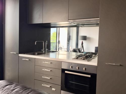uma cozinha com um lavatório e um fogão forno superior em Modern Luxurious with private parking on premises and fast internet em Melbourne