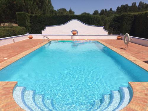 a large swimming pool with blue water on a wooden deck at Quarto Monte Ninho das Perdizes in Cercal
