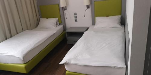 two beds in a room with green and white at Hotel Altbacher Hof in Altbach