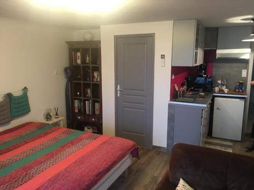 ein kleines Schlafzimmer mit einem Bett und einer Küche in der Unterkunft Petit nid douillet in Cambo-les-Bains