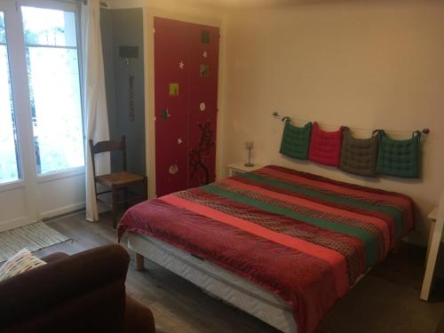 ein Schlafzimmer mit einem Bett mit bunten Kissen darauf in der Unterkunft Petit nid douillet in Cambo-les-Bains