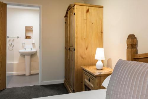 a bedroom with a bed and a sink and a bathroom at Roydon Marina Village Hotel in Roydon