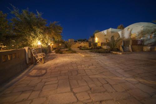 a stone patio at night with a building and trees at Rahala Safari Hotel in Qasr Al Farafirah