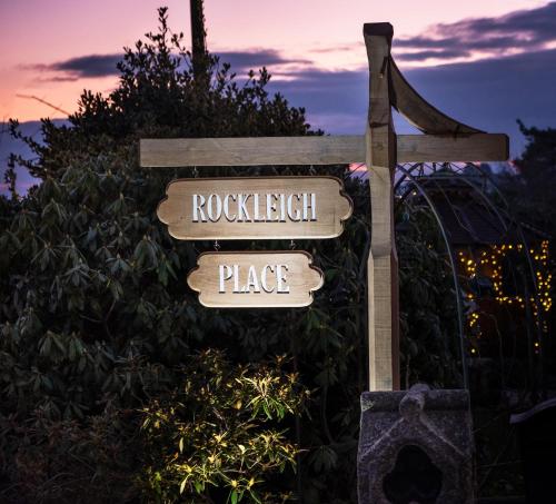 a wooden sign for rockwell place in front of a bush at Rockleigh Place in St Austell