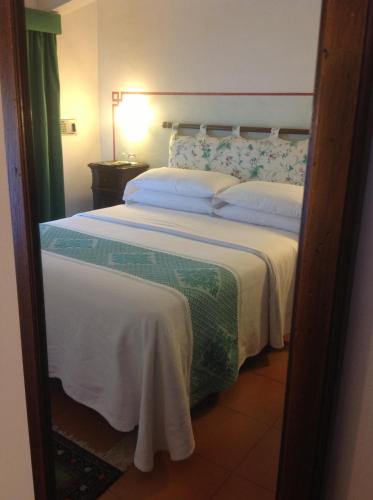a bedroom with a large bed with white sheets at Villa Acquaviva Wine Resort in Montemerano