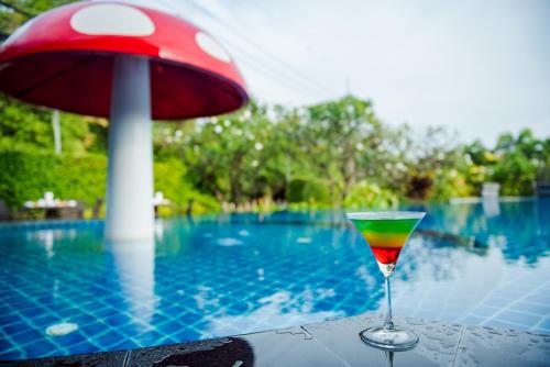 a martini glass sitting on a table next to a pool at Golden Beach Cha-Am Hotel in Cha Am