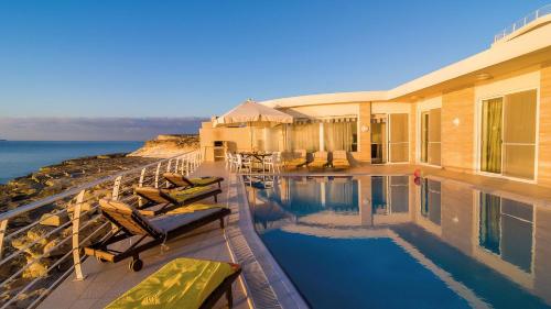 a house with a swimming pool next to the ocean at Villa Watersedge in Marsaskala