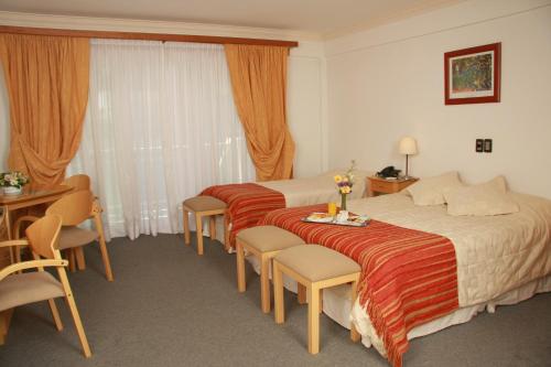 a hotel room with two beds and a table and chairs at Hotel Ayres Del Nahuel in San Carlos de Bariloche