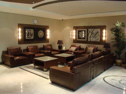 a living room with leather furniture and a clock on the wall at Manazilna Apartments Riyadh منازلنا للشقق المفروشة in Riyadh