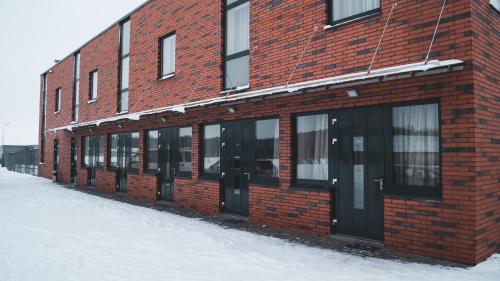 a red brick building with black doors in the snow at Vlantana in Klaipėda