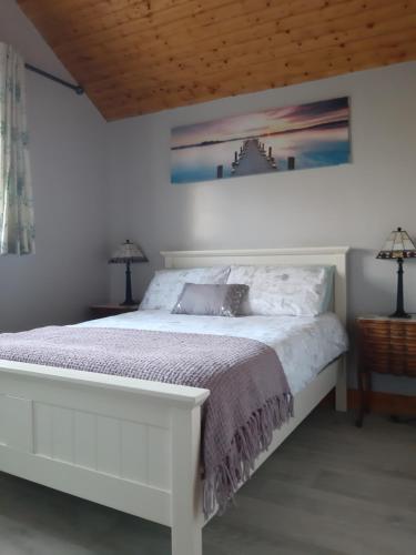 a bedroom with a white bed and two lamps at An Crann Glas in Galway