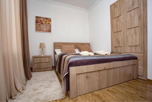 een slaapkamer met een bed met een houten hoofdeinde bij Tbilisi Central apartment in Tbilisi City