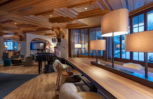a lobby with a large table and chairs and windows at Sunstar Hotel & SPA Grindelwald in Grindelwald