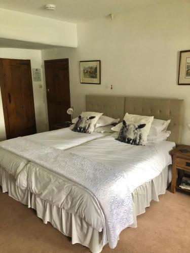 a large white bed with two dogs on the pillows at Holmeshead Farm in Ambleside