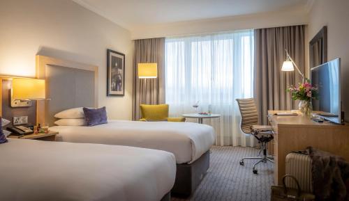 a hotel room with two beds and a desk at Clayton Hotel Burlington Road in Dublin