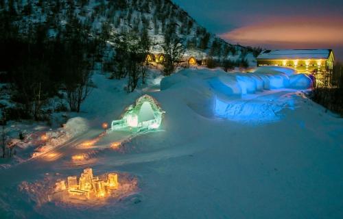 a resort covered in snow at night with lights at Snowhotel Kirkenes in Kirkenes