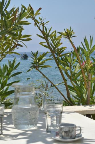 a table with water glasses and a boat in the water at ''Sea front'' Rose's house in Kardiani