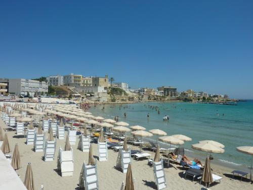 a beach with chairs and umbrellas and people in the water at Life's Hotel B in Minervino di Lecce