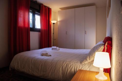 - une chambre avec un lit doté de rideaux rouges et d'une lampe dans l'établissement Ca' Bianca Relax Apartment, sur le Lido de Venise