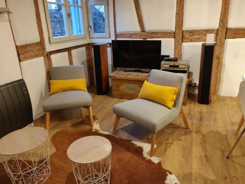 a living room with two chairs and a tv at Elsass Design Hygge in Eguisheim